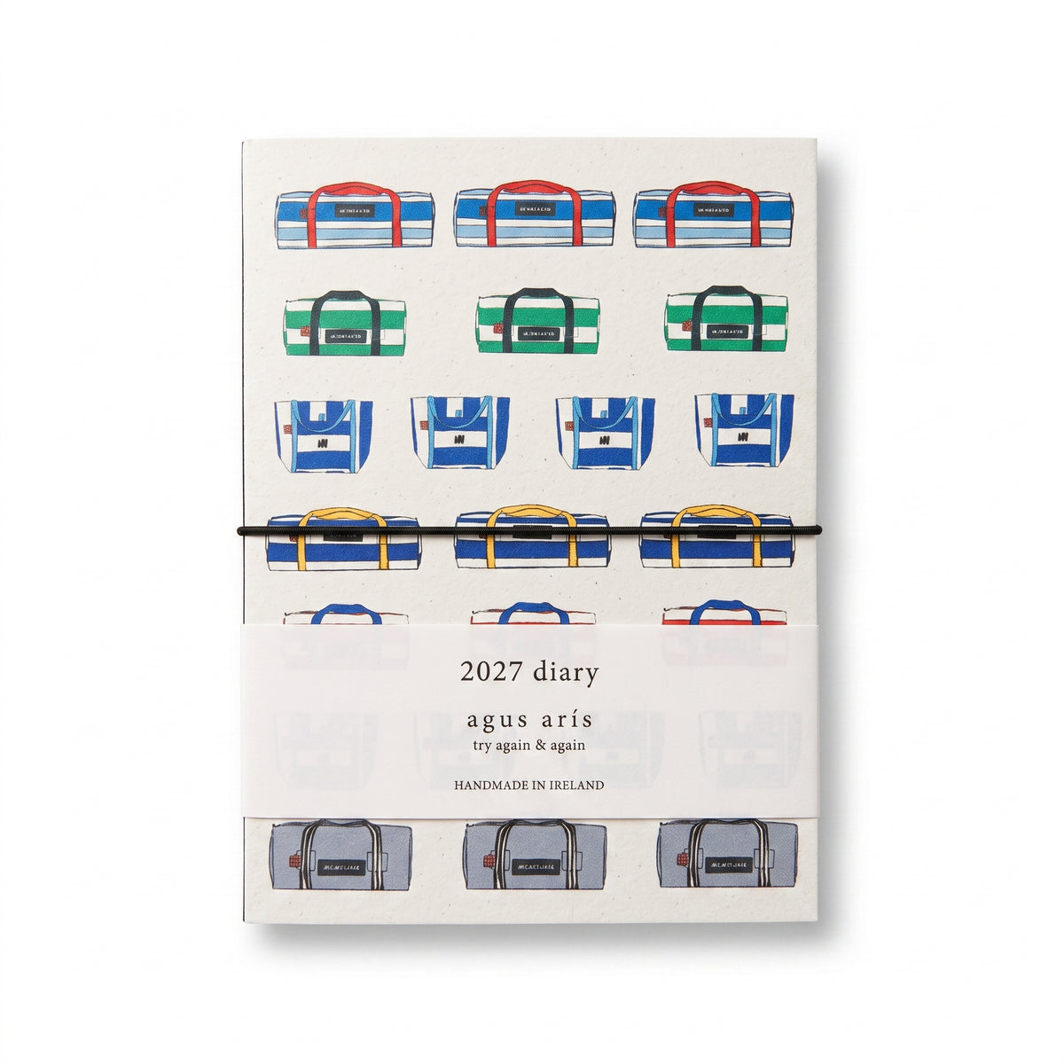A 2027 daily planner by Agus Aris, featuring an illustration of colorful duffel bags on the cover, wrapped in a white paper band with the brand name 'agus aris' printed on it.