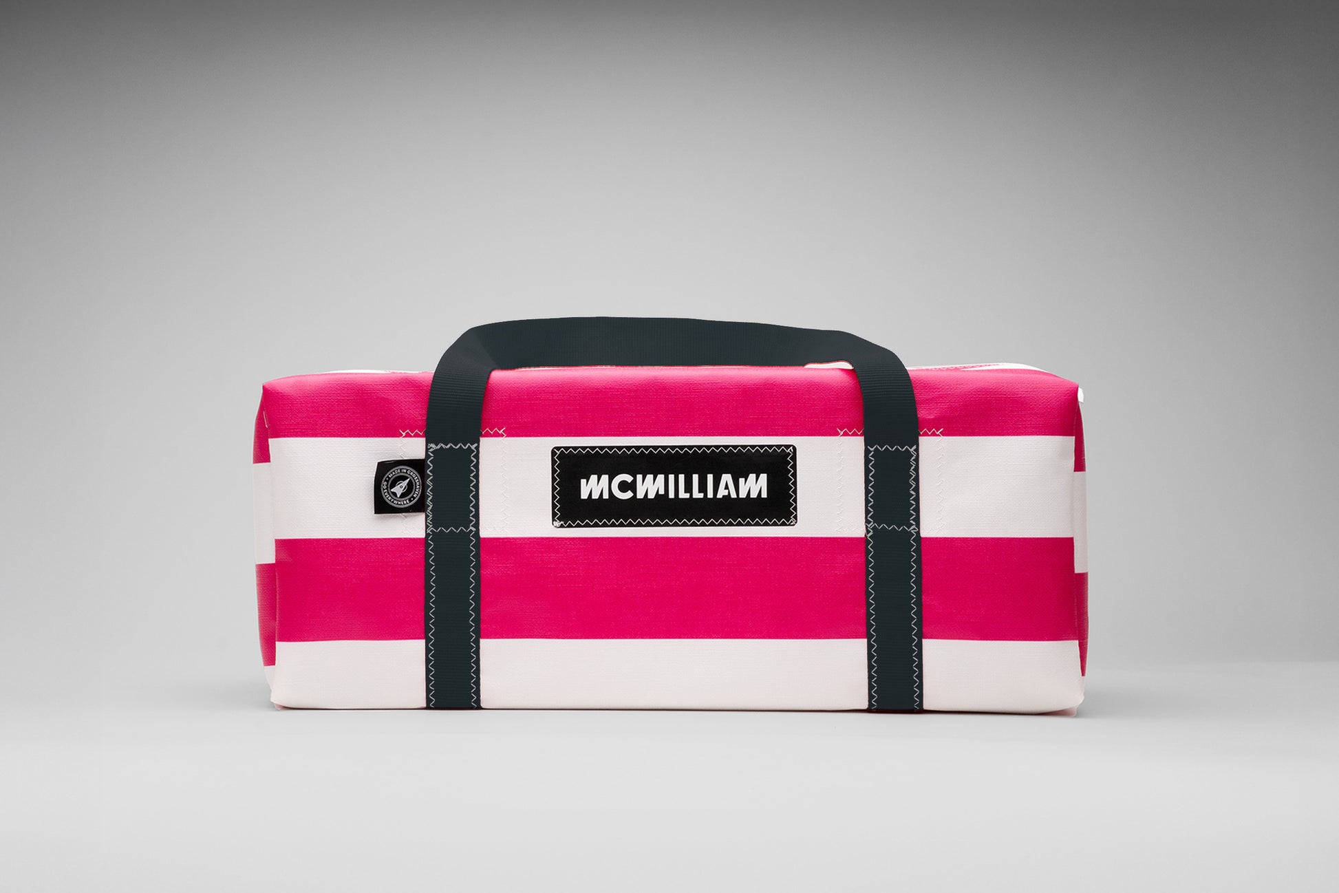 Pink and white striped bag with black straps on a gray background