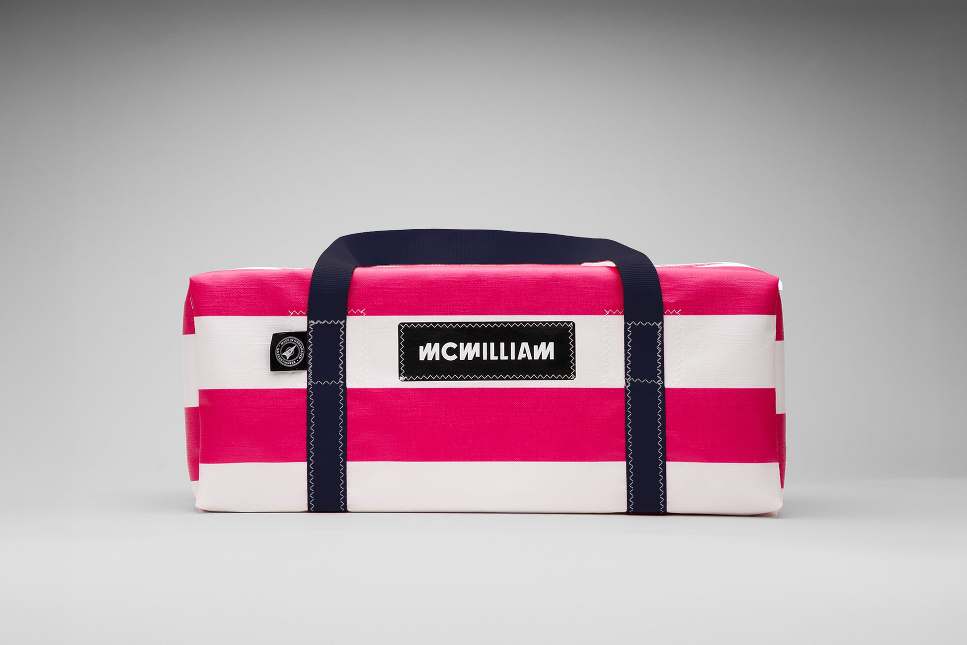 Pink and white striped bag with navy straps on a gray background