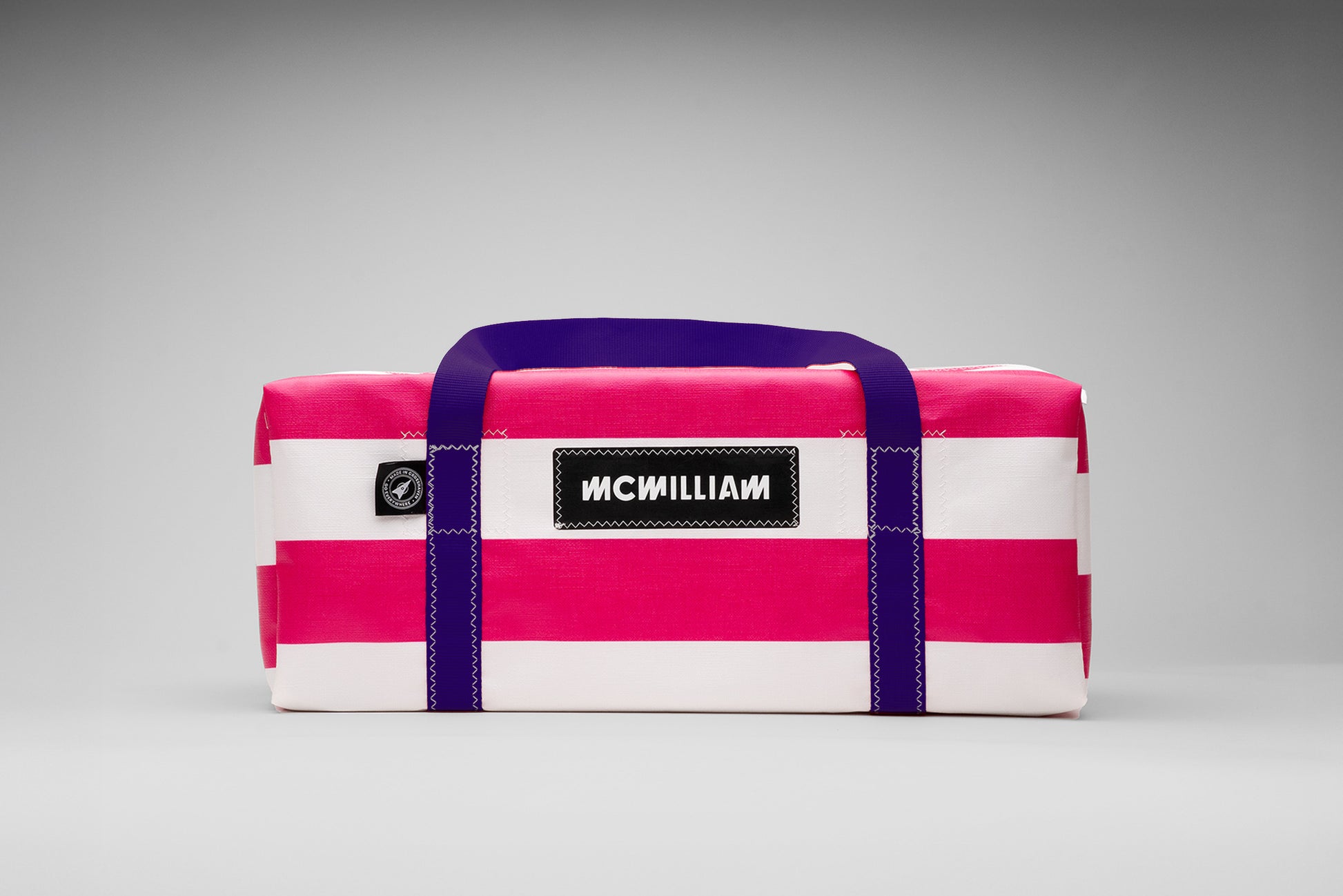 Pink and white striped bag with purple handles on a gray background