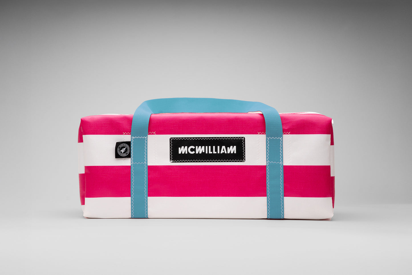 Pink and white striped cooler bag with blue straps on a gray background