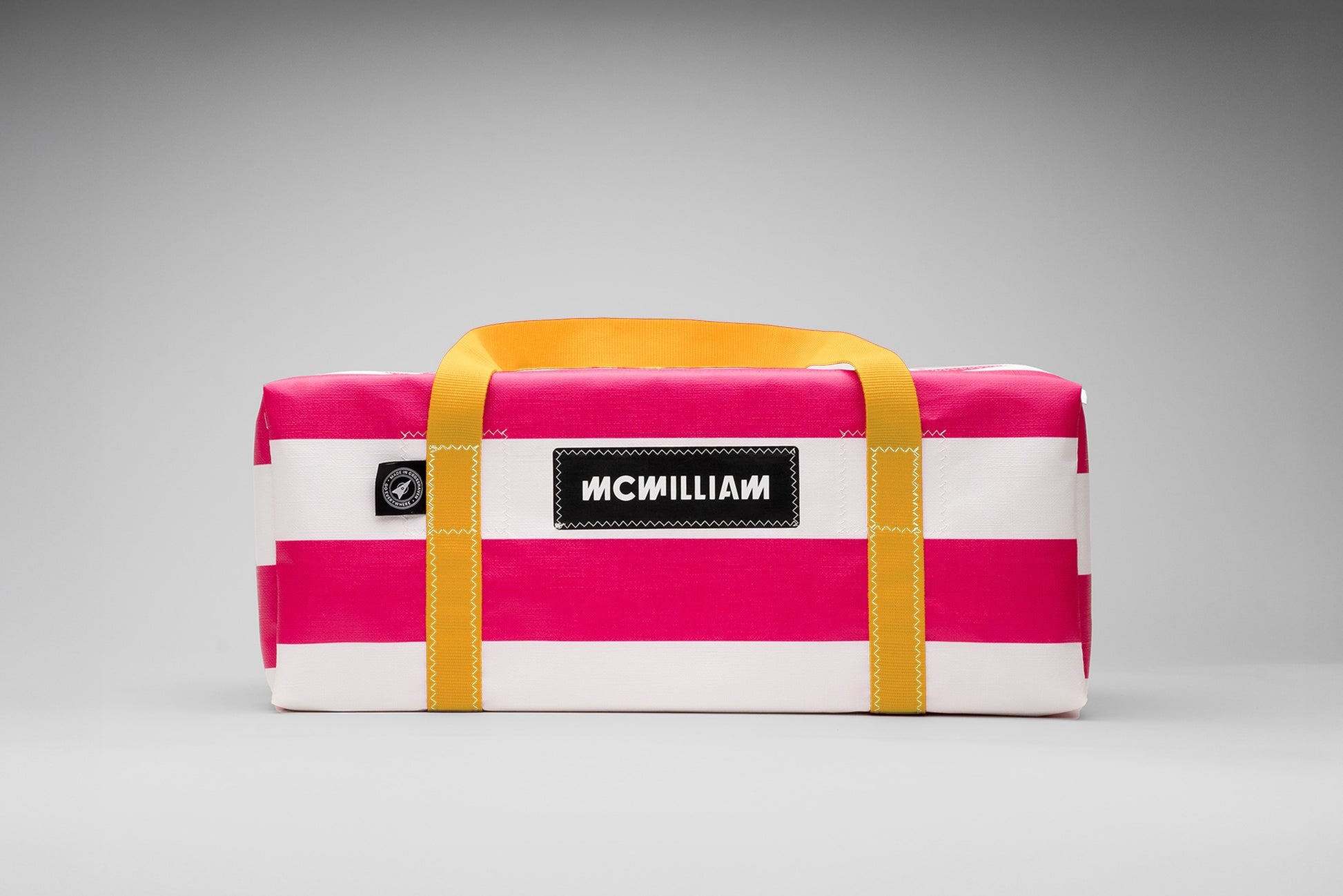 Pink and white striped bag with yellow straps on a gray background