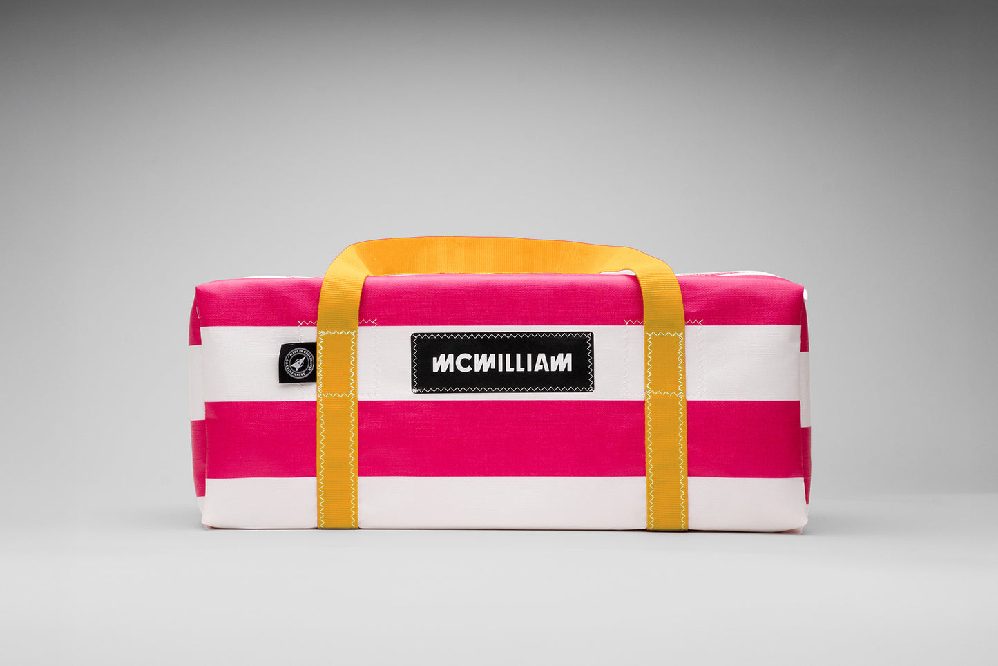 Pink and white striped bag with yellow straps on a gray background
